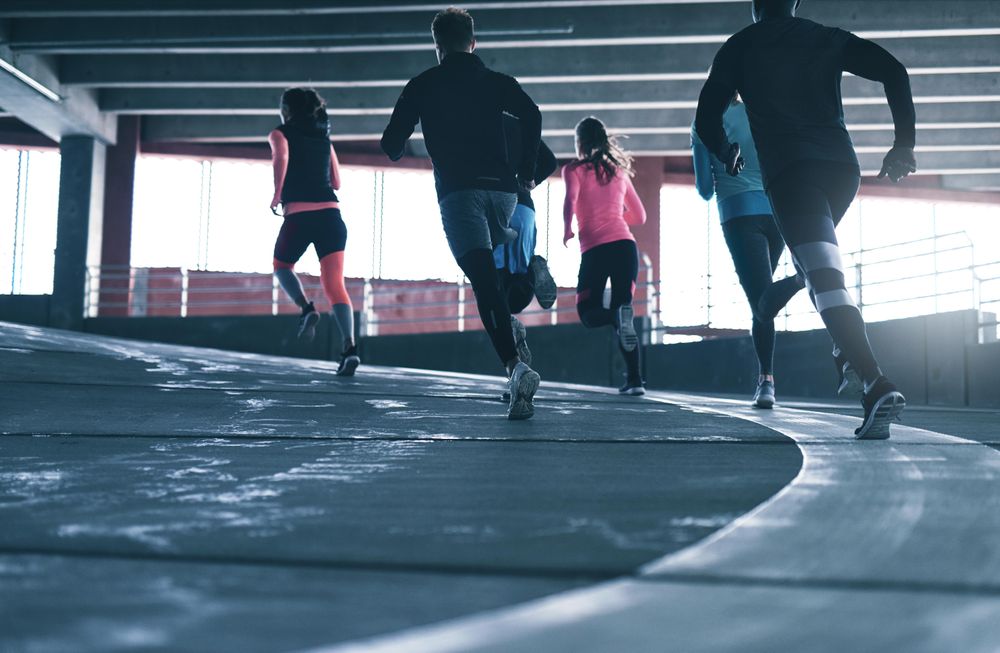 Group of people running up an incline on an indoor track
