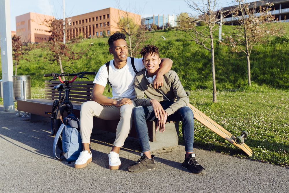 Young Black men playing on street bench