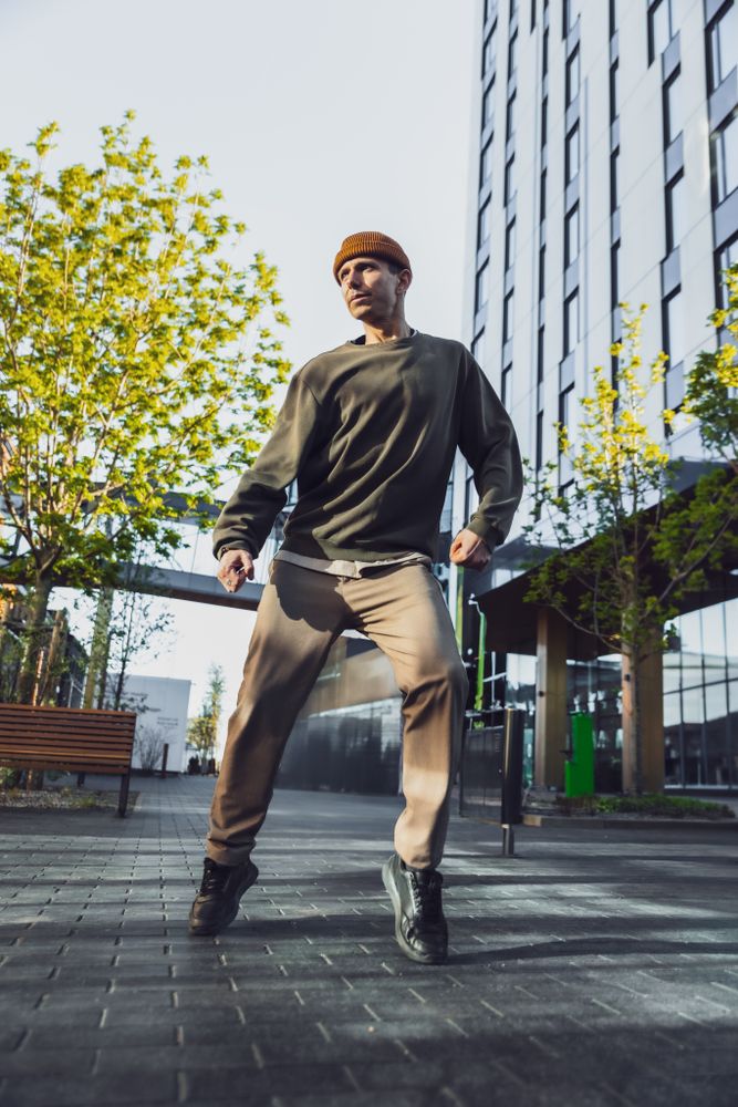 Vertical Screen: A Young Man In Stylish Outfit Performs An Energetic Breakdance Or Hip-Hop Move In A Sunny Plaza