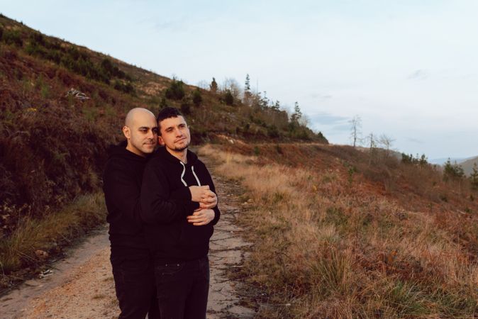 Men hugging on road on hill