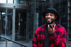 Cheerful Black man talking on smartphone on street
