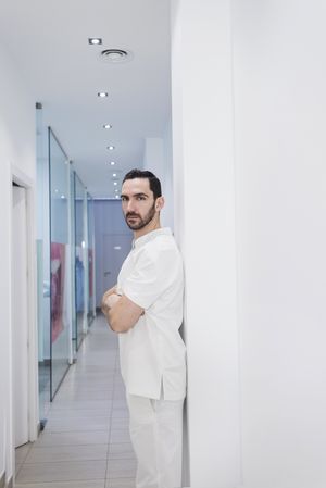 Portrait of a bearded doctor standing in the hospital hallway while looking camera