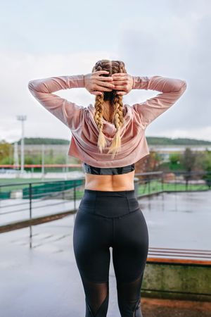Young sportswoman stretching neck and shoulders outdoors