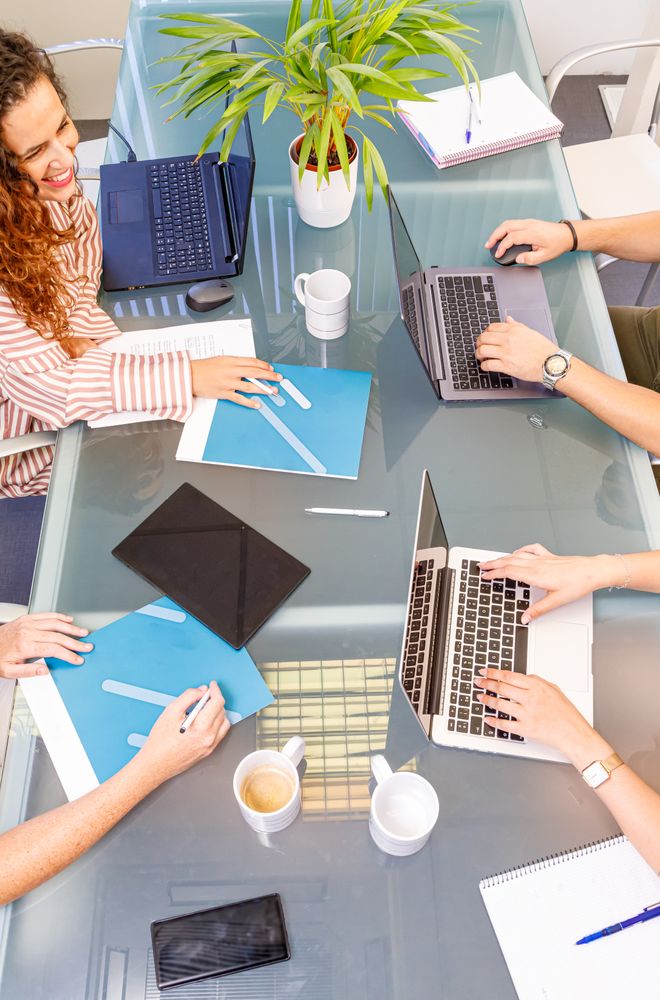 Faceless colleagues working at laptops in office