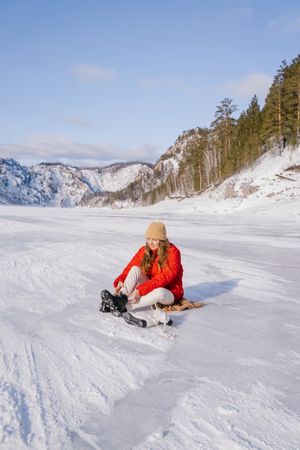 Woman sitting on snow and changing boots
