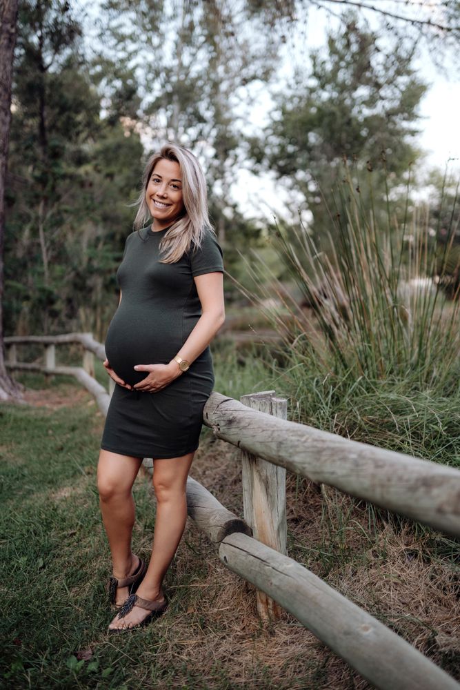 Happy pregnant woman standing at river in park