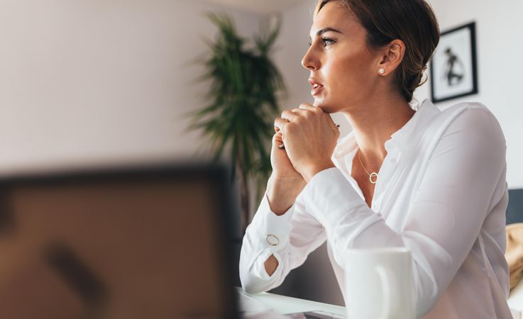 Woman sitting at her desk in office thinking deeply