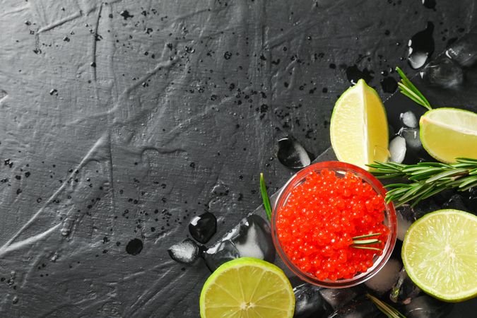 Fresh composition with caviar and citrus on dark table, top view