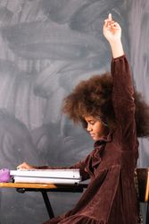 Black girl with raised hand in classroom during lesson
