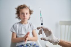 Faceless medic with syringe near child
