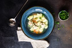 Bowl of hearty soup with potato and carrot and meat balls served on the table with copy space