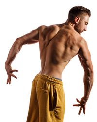 Bodybuilder practicing poses ahead of competition in light studio