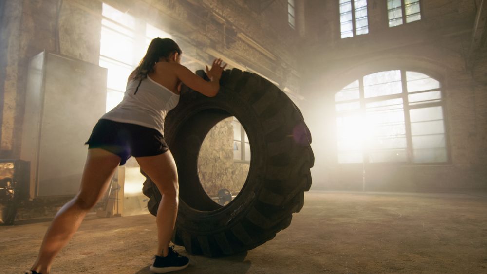 Fit Athletic Woman Lifts Tire as Part of Her Cross Fitness  Bodybuilding Training.