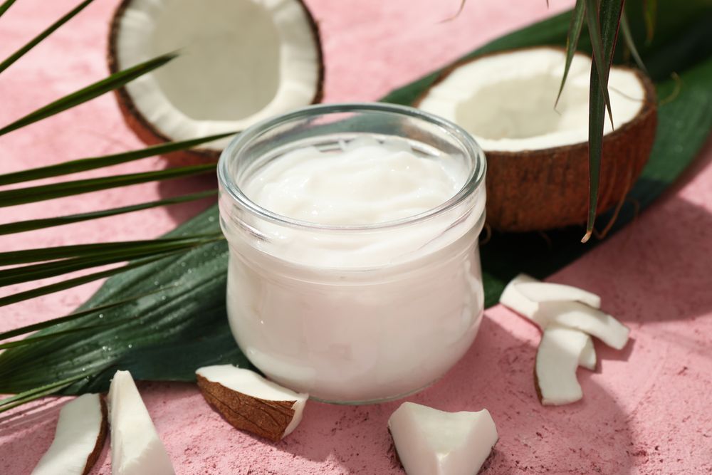 Coconut and cosmetics on pink background, close up