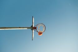 Ball above basketball ring against blue sky