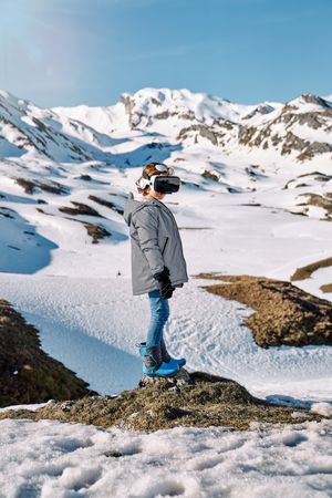 Unrecognizable boy in VR headset on snowy mountains