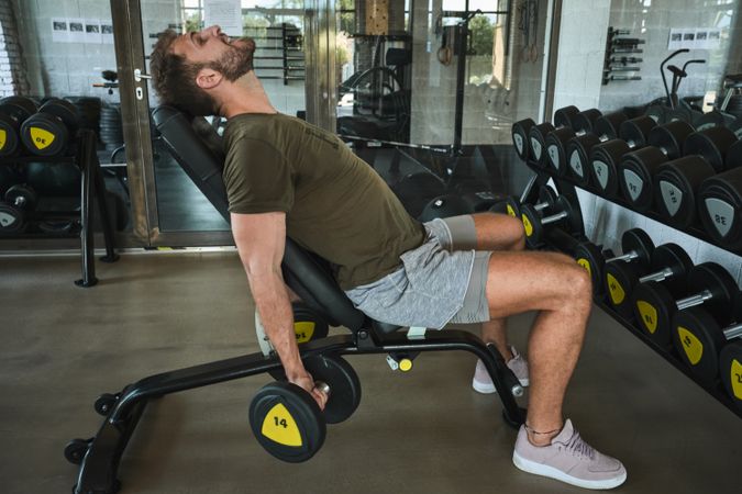 Strong man exercising with dumbbells in gym