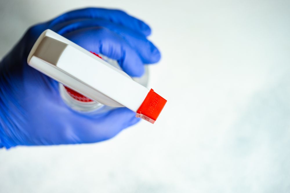 Top view of hands in latex gloves holding spray bottle