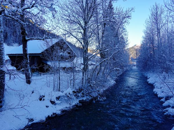 Snow covered barn next to the river La Sarine, Gstaad