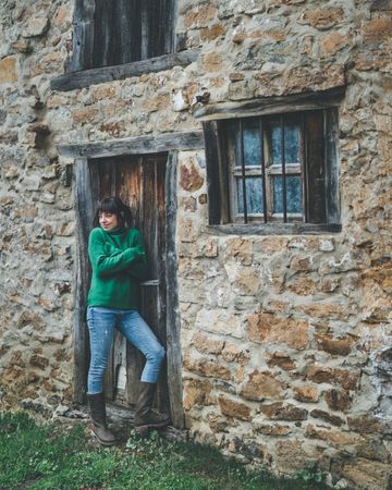 Young woman standing in door of old country house