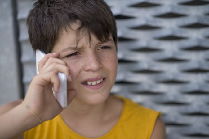 Teenage boy in yellow shirt talking on phone