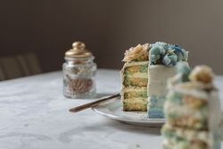 Portion of rainbow cake, filled with chantilly cream, and decorated with buttercream flowers
