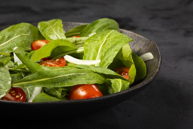 Arugula salad with tomatoes on dark background.