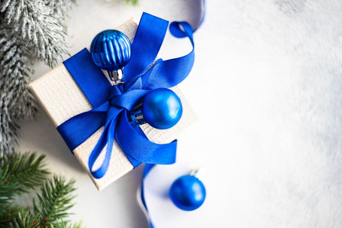 Christmas present with blue ribbon and baubles with copy space