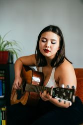 Young woman playing guitar inside house