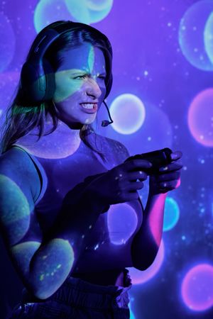 Angry woman playing videogame under colorful sparkles