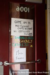 Handwritten signs on coffee shop door with coronavirus restrictions 0Ld7r0
