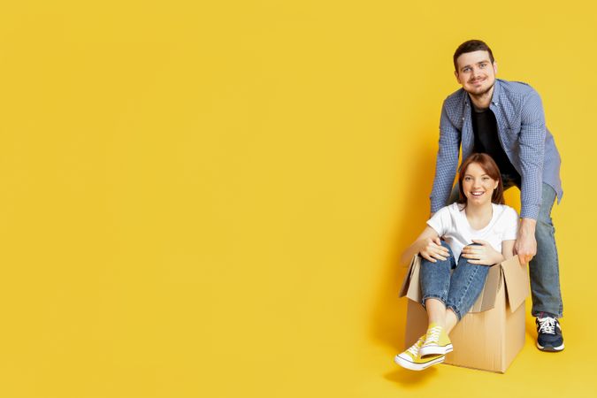 A couple with boxes, on a yellow background, the concept of moving.