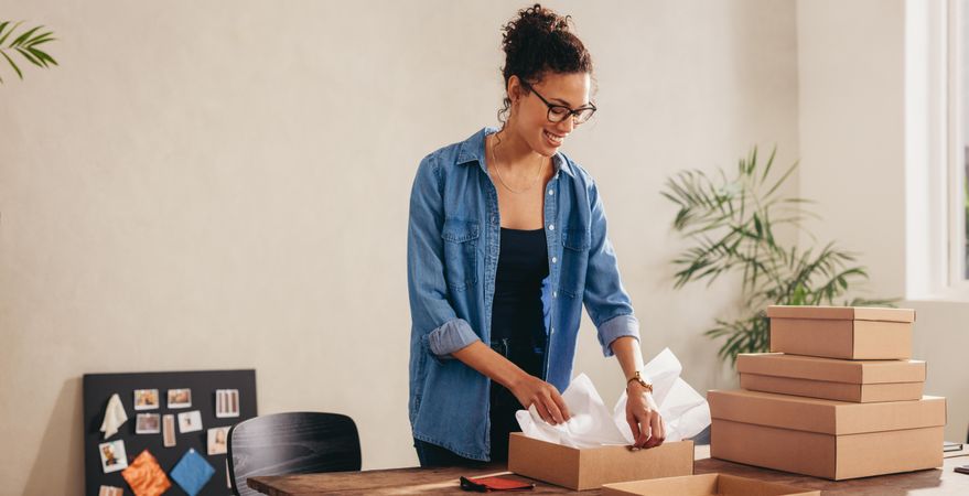 Woman packing the cardboard box on her desk at home