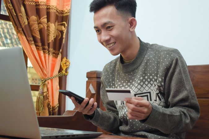 Asian man shopping online holding credit card and smartphone