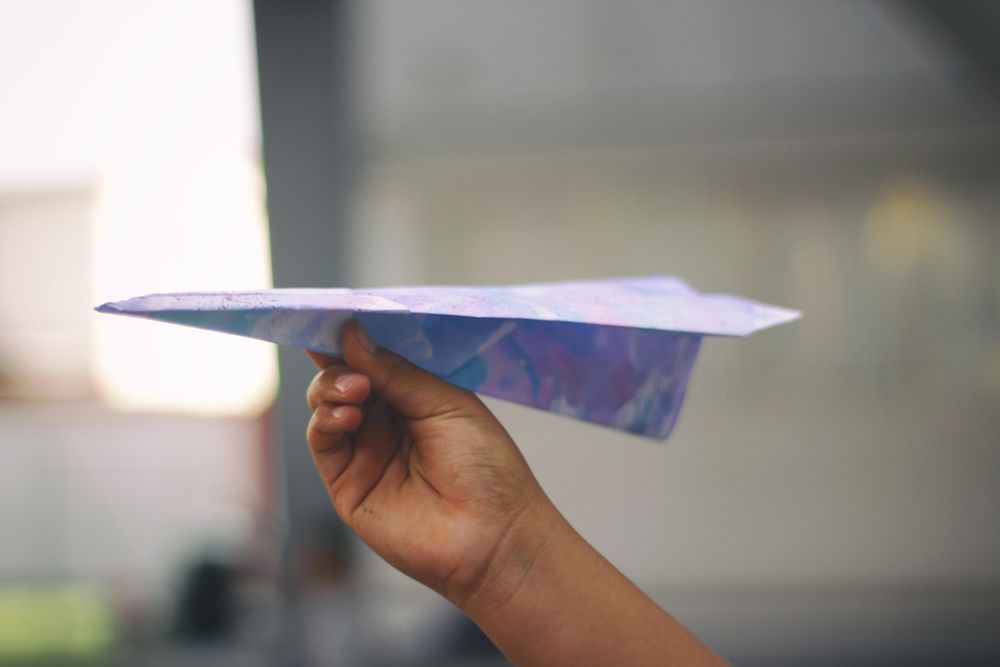 Child's hand holding paper plane