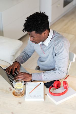 Black financial employee working on laptop at home