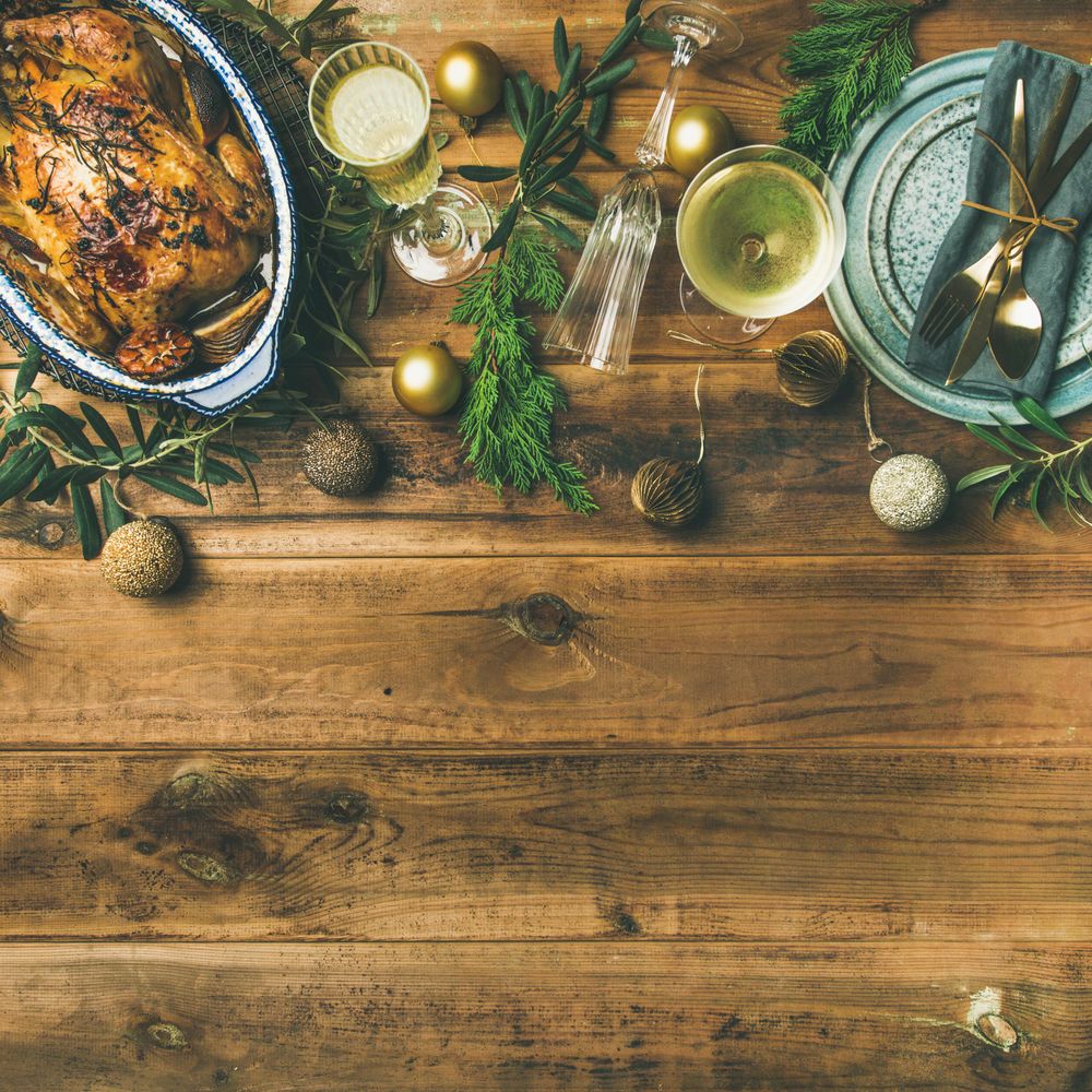 Roast chicken, plate, festive decorations, crystal flutes on wooden table, square crop