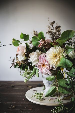 Composition of flowers and plants in vintage vase on board