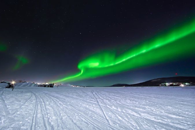 Polar lights over trees in winter countryside