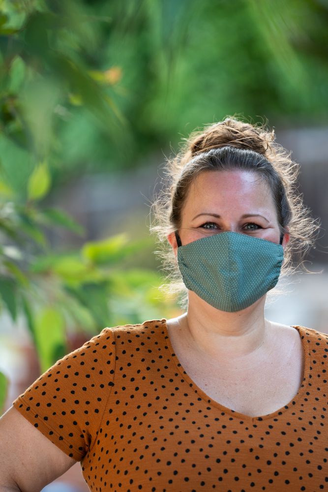 Portrait of beautiful woman in cotton PPE mask smiling and looking at camera