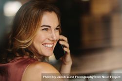 Portrait of a happy woman holding a phone to her ear bG9gX5