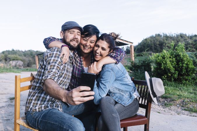 A group of friends sitting outdoors while taking a selfie