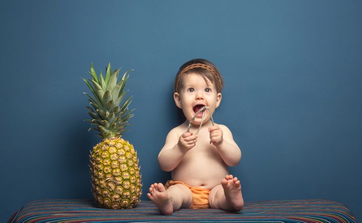 Happy baby playing with a pineapple