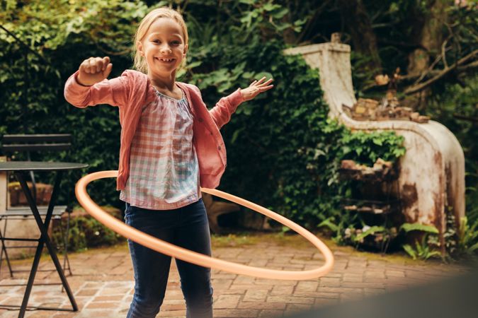 Smiling girl playing with hula hoop outside