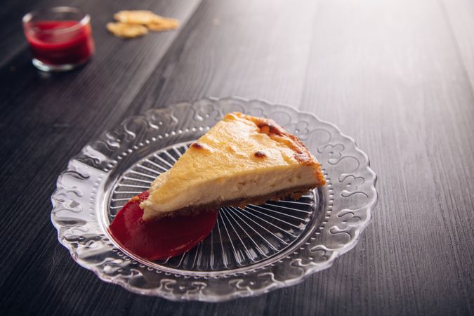 Baked cheesecake with red jam in glass plate