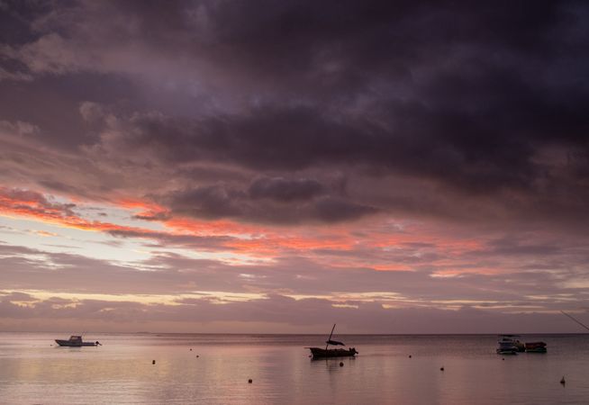 Boats parked at sunset under a pink sky