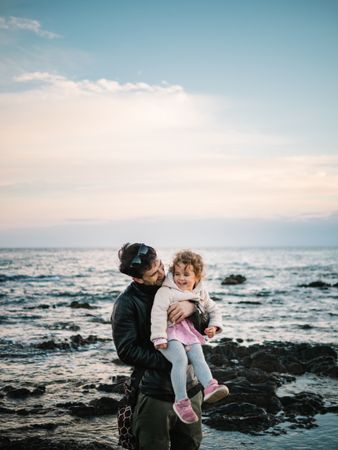 father holding little daughter at the beach