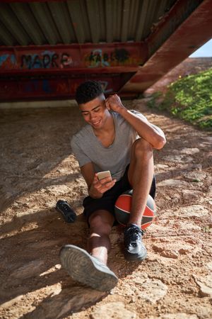 Cheerful Hispanic sportsman browsing smartphone