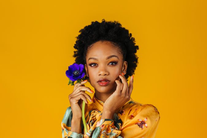 Beautiful Black woman holding blue flower to her face