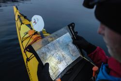 Man reading map and kayaking on water